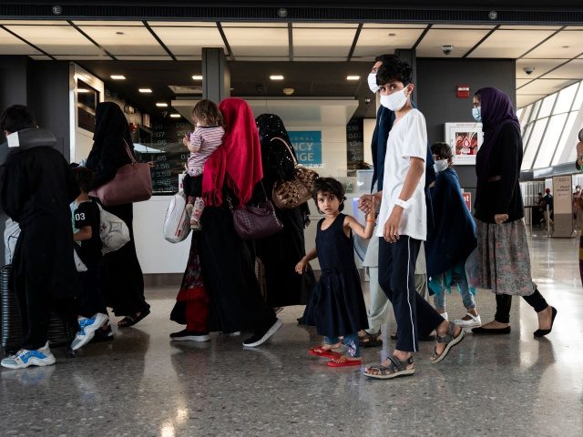 Refugees from Afghanistan are escorted to a waiting bus after arriving and being processed at Dulles International Airport in Dulles, Virginia on August 23, 2021. - Around 16,000 people were evacuated over the past 24 hours from Afghanistan through the Kabul airport, the Pentagon said on August 23, 2021, as …