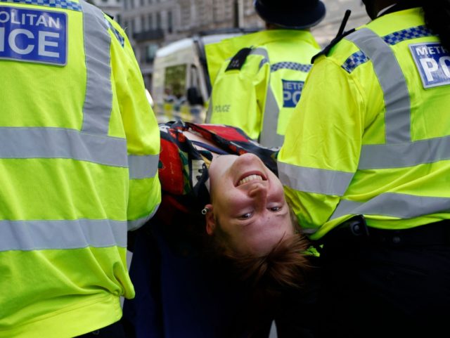 Police officers carry a climate activist from Extinction Rebellion during the group's