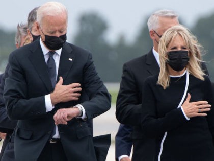 US President Joe Biden looks down alongside First Lady Jill Biden as they attend the digni