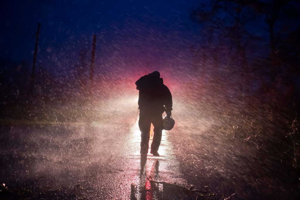 TOPSHOT - Montegut fire chief Toby Henry walks back to his fire truck in the rain as firefighters cut through trees on the road in Bourg, Louisiana as Hurricane Ida passes on August 29, 2021. - Hurricane Ida struck the coast of Louisiana on August 29 as a powerful Category 4 storm, 16 years to the day after deadly Hurricane Katrina devastated the southern US city of New Orleans."Extremely dangerous Category 4 Hurricane Ida makes landfall near Port Fourchon, Louisiana," the National Hurricane Center wrote in an advisory. (Photo by Mark Felix / AFP) (Photo by MARK FELIX/AFP via Getty Images)