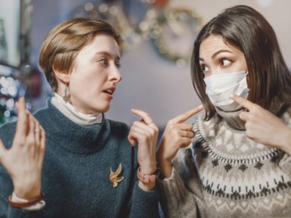 Asian woman in a medical mask argues and fights with her opponent, who does not believe in the coronavirus and the covid-19 pandemic and does not comply with the rules and restrictions.