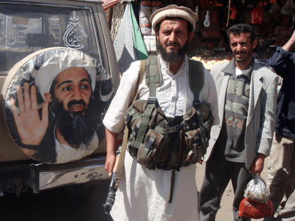 A fighter is seen standing in front of an image of Osama bin Laden, the late head of al-Qa