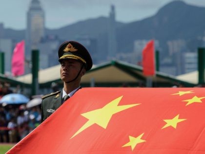 A PLA soldier stands to attention with the Chinese flag during the open day of the Chinese People's Liberation Army (PLA) Navy Base at Stonecutter Island in Hong Kong on July 1, 2016, to mark the 19th anniversary of the Hong Kong handover to China. / AFP / Anthony Wallace …
