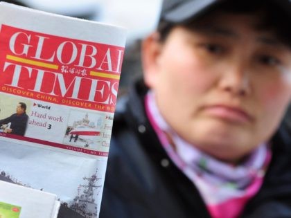 A news vendor places a copy of the Global Times for display on her newsstand in Beijing on