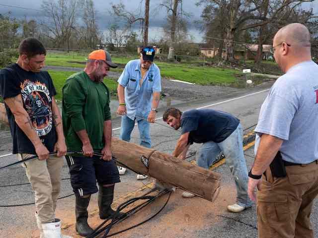 People work together to clear a telephone pole off the road in Bourg, Louisiana on August