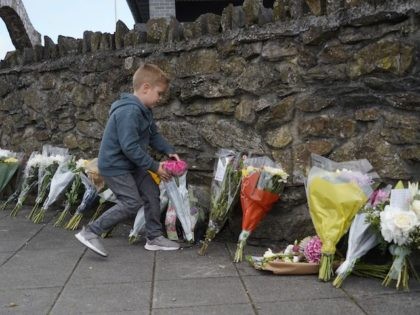 Floral tributes are placed on a pavement near the scene of a shooting incident in Plymouth