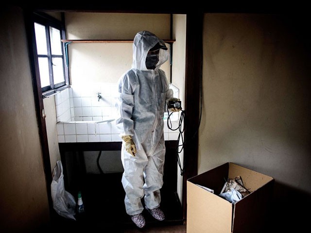 TOPSHOT - In this picture taken on August 19, 2017, a worker for special cleaning, wearing a protective suit, takes pictures of a man's apartment who died alone and left decomposing for three weeks, in Tokyo. There are no official data for the number of people dying alone who stay unnoticed for days and weeks but most experts estimate it at 30,000 per year in Japan. The man, believed to be in his 50s, died alone in a city he shared with 13 million people but no one noticed, making him the latest victim of "kodokushi" or "dying alone" -- a growing trend in ageing Japan. / AFP PHOTO / BEHROUZ MEHRI / TO GO WITH AFP STORY JAPAN-DEATH-SOCIAL,FEATURE BY HIROSHI HIYAMA (Photo credit should read BEHROUZ MEHRI/AFP via Getty Images)