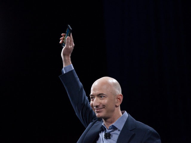 Jeff Bezos holds up an Amazon device (David Ryder /Getty)