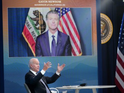 US President Joe Biden speaks as California Governor Gavin Newsom. on a screen, looks on d