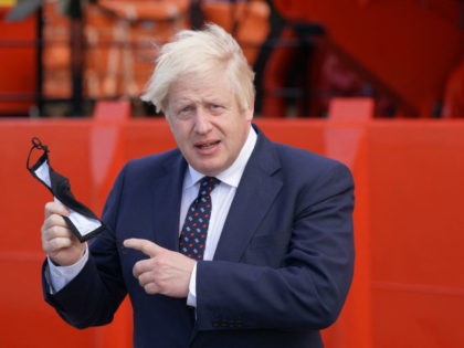 Britain's Prime Minister Boris Johnson holds his face mask before boarding the vessel Alba