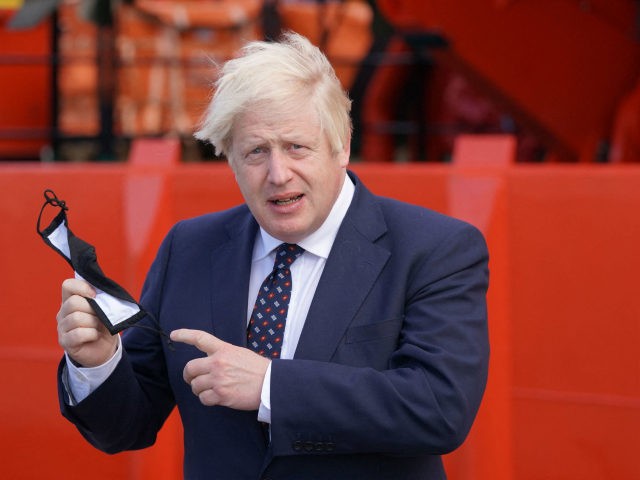Britain's Prime Minister Boris Johnson holds his face mask before boarding the vessel Alba