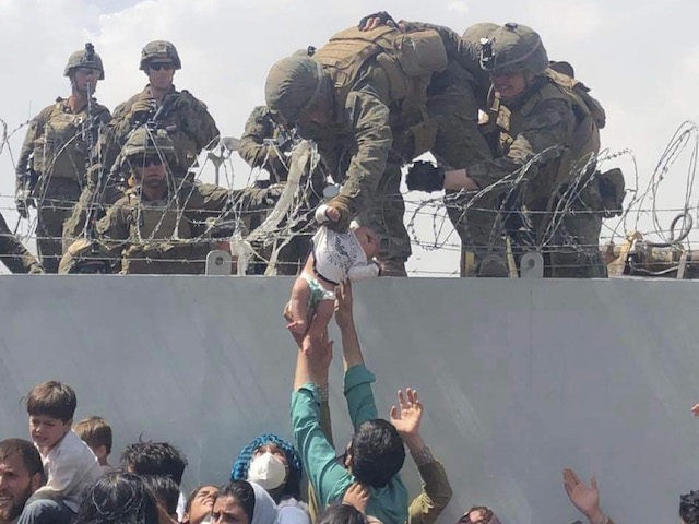 TOPSHOT - This image made available to AFP on August 20, 2021 by Omar Haidiri, shows a US Marine grabbing an infant over a fence of barbed wire during an evacuation at Hamid Karzai International Airport in Kabul on August 19, 2021. - A Pentagon official confirmed Friday that US …