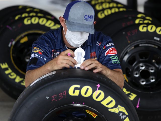 DARLINGTON, SOUTH CAROLINA - MAY 19: A crew member in a mask checks the tires in the garag