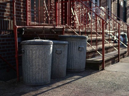 A row of old metal garbage cans outside an urban neighborhood home along a sidewalk in Ast