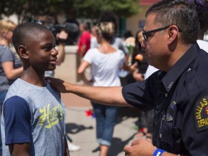 A police officer talks with a boy at the memorial at Dallas Police Headquarters on July 8, 2016. The gunman who opened fire on Dallas officers during a protest against US police brutality, leaving five dead and seven others wounded, told negotiators he wanted to kill white cops, the city's …