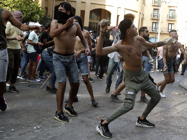 Anti-government protesters throw stones toward riot police during a protest marking the fi