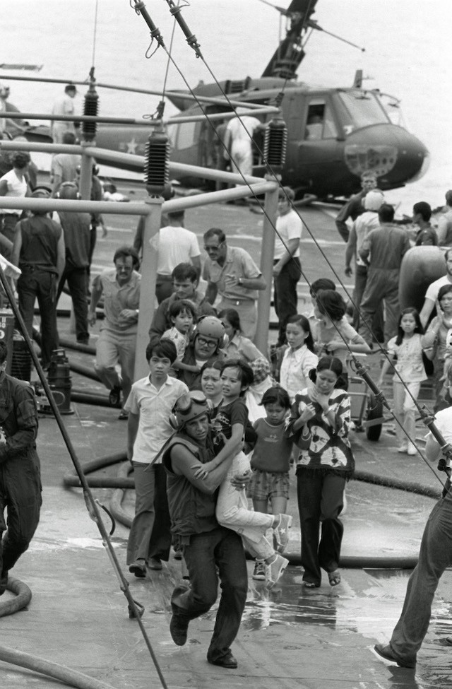 U.S. Marine helicopter crewmen carry Vietnamese civilians to safety aboard the U.S.S. Blue Ridge April 29, 1975, after their evacuation helicopter crashed on the deck of the amphibious command ship. (AP Photo)