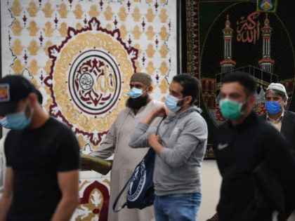 Worshippers wearing facemasks wait to leave following Friday prayers at Madina Masjid, She