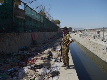 A Taliban fighter stands guard at the site of the August 26 twin suicide bombs, which kill