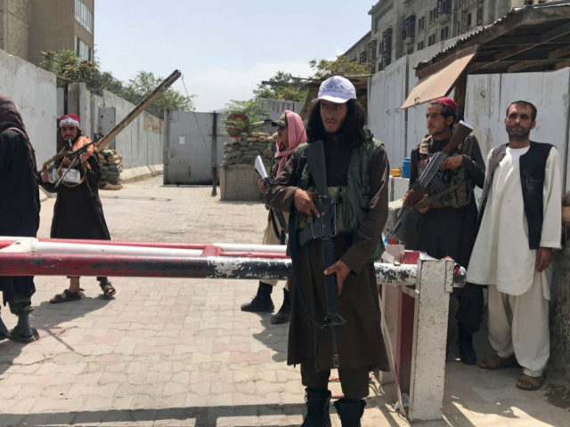 Taliban fighters stand guard at a checkpoint near the US embassy that was previously manne