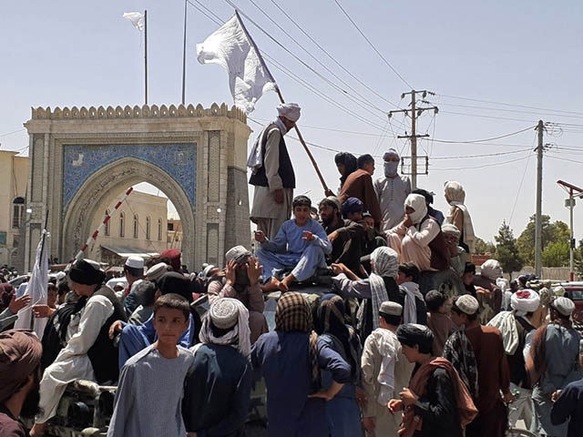 TOPSHOT - Taliban fighters stand on a vehicle along the roadside in Kandahar on August 13,