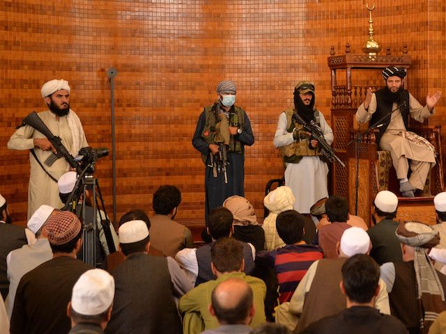 Armed Taliban fighters stand next an Imam during Friday prayers at the Abdul Rahman Mosque in Kabul on August 20, 2021, following the Taliban