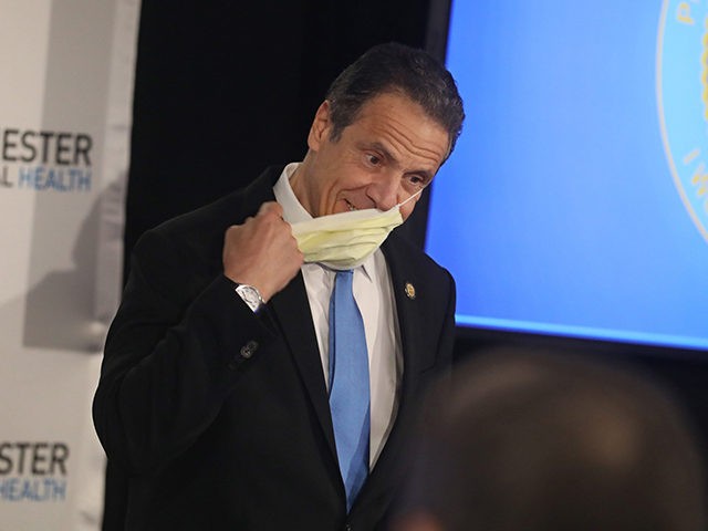 Governor Andrew Cuomo takes off his face mask as he enters to give his daily briefing on t