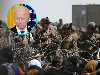 US soldiers stand guard behind barbed wire as Afghans sit on a roadside near the military