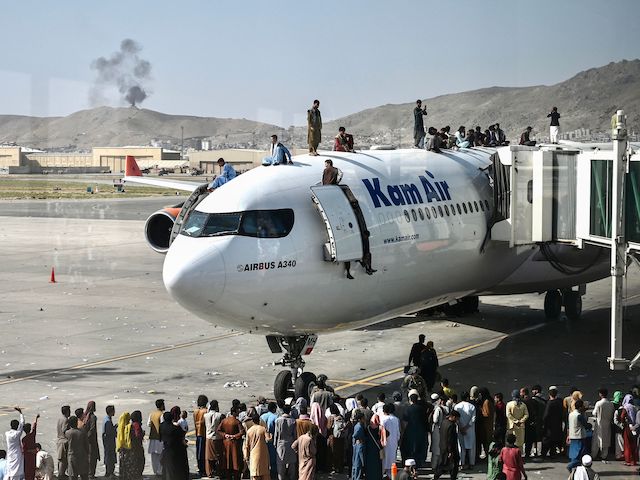 TOPSHOT - Afghan people climb atop a plane as they wait at the Kabul airport in Kabul on August 16, 2021, after a stunningly swift end to Afghanistan's 20-year war, as thousands of people mobbed the city's airport trying to flee the group's feared hardline brand of Islamist rule. (Photo by Wakil Kohsar / AFP) (Photo by WAKIL KOHSAR/AFP via Getty Images)