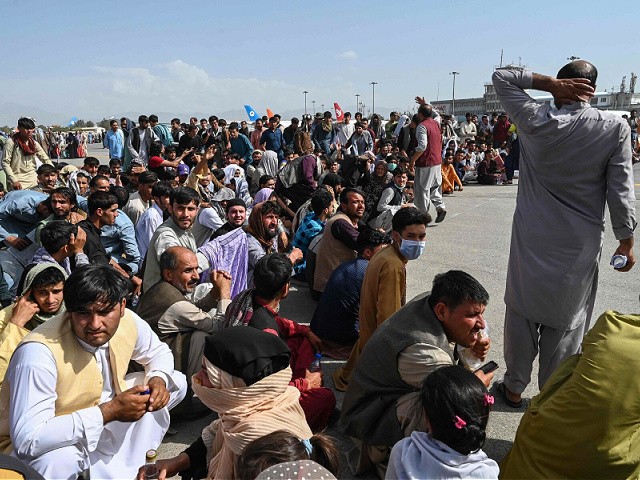 TOPSHOT - Afghan passengers sit as they wait to leave the Kabul airport in Kabul on August 16, 2021, after a stunningly swift end to Afghanistan's 20-year war, as thousands of people mobbed the city's airport trying to flee the group's feared hardline brand of Islamist rule. (Photo by Wakil Kohsar / AFP) (Photo by WAKIL KOHSAR/AFP via Getty Images)