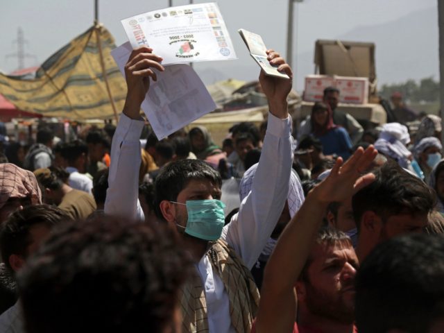 Hundreds of people gather, some holding documents, near an evacuation control checkpoint o