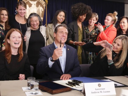 Surrounded by supporters and activists, New York Gov. Andrew Cuomo signs a bill that incre