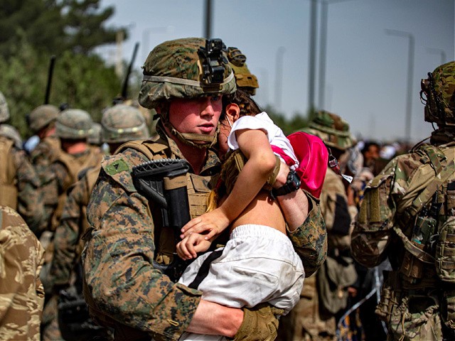 In this Aug. 20, 2021, photo provided by the U.S. Marine Corps, a Marine assigned to the 24th Marine Expeditionary Unit carries a girl at a gate to Hamid Karzai International Airport in Kabul, Afghanistan. (1st Lt. Mark Andries/U.S. Marine Corps via AP)