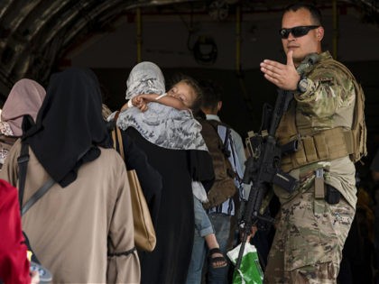 In this image provided by the U.S. Air Force, a U.S. Air Force Airman guides evacuees aboard a U.S. Air Force C-17 Globemaster III at Hamid Karzai International Airport in Kabul, Afghanistan, Tuesday, Aug. 24, 2021. (Senior Airman Taylor Crul/U.S. Air Force via AP)