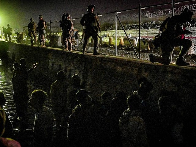 In this picture taken in the late hours on August 22, 2021 British and Canadian soldiers stand guard near a canal as Afghans wait outside the foreign military-controlled part of the airport in Kabul, hoping to flee the country following the Taliban's military takeover of Afghanistan. (Photo by WAKIL KOHSAR / AFP) (Photo by WAKIL KOHSAR/AFP via Getty Images)