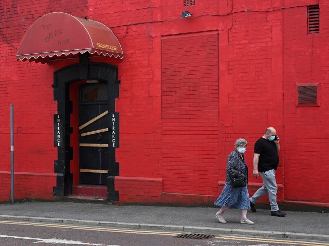 Pedestrians wearing face coverings due to Covid-19, walk past a closed-down nightclub in B