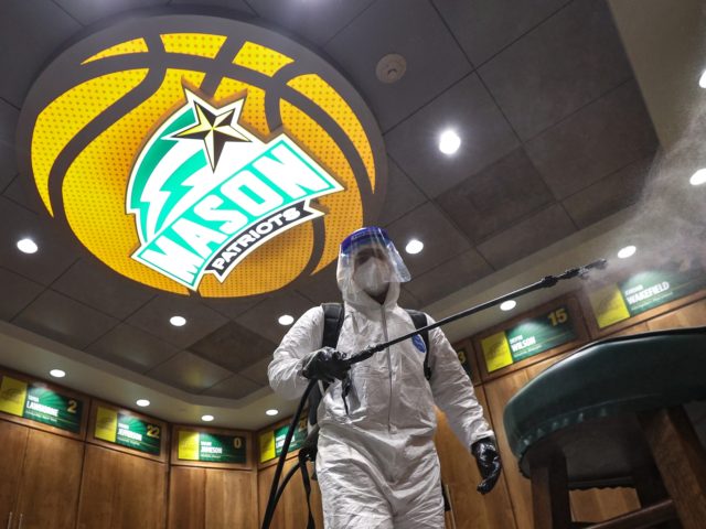 FAIRFAX, VIRGINIA - JANUARY 13: Alexander Espinoza of V&G Cleaning Services uses an electromagnetic sanitizer with hospital-grade disinfectant to sterilize the George Mason Patriots basketball locker room against the novel coronavirus after their men's NCAA basketball game against the La Salle Explorers at Eagle Bank Arena on January 13, 2021 in …