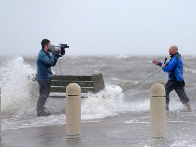 A news crew films as storm surge pushes water from Lake Pontchartrain over Lakeshore Drive