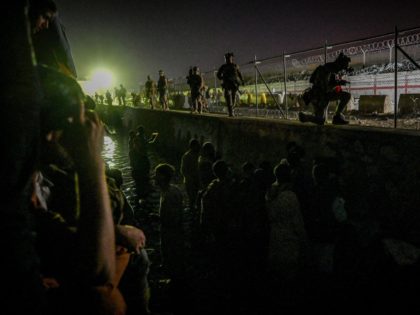 In this picture taken in the late hours on August 22, 2021 British and Canadian soldiers stand guard near a canal as Afghans wait outside the foreign military-controlled part of the airport in Kabul, hoping to flee the country following the Taliban's military takeover of Afghanistan. (Photo by Wakil KOHSAR …
