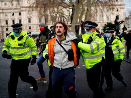 Police officers arrest a protestor during an anti-COVID-19 lockdown demonstration outside the Houses of Parliament in Westminster, central London on January 6, 2021. - Britain toughened its coronavirus restrictions on Tuesday, with England and Scotland going into lockdown and shutting schools, as surging cases have added to fears of a …