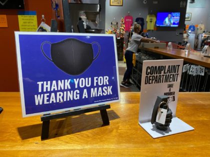 Wearing a mask, a worker at Dodge City Brewing in Kansas cleans the bar behind a sign reminding customers they are required to wear a mask inside when not eating or drinking, next to a \"complaint department\" sign with a mock grenade. Xxx Xxx Th Dodge City Coronavirus 666 Jpg …