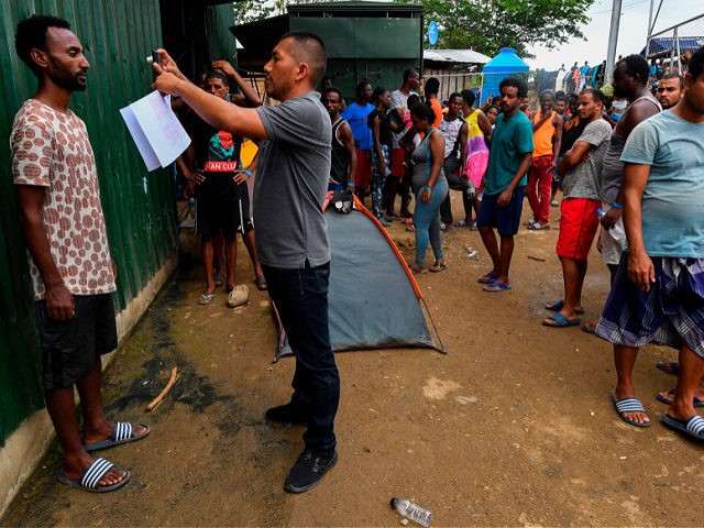 A member of Panama's National Borders Service takes a picture of a migrant at the Temporary Station of Humanitarian Assistance (ETAH) in La Penita village, Darien province, Panama on May 23, 2019. - Migrants mainly from Haiti, Cuba, Democratic Republic of Congo, India, Cameroon, Bangladesh and Angola cross the border …