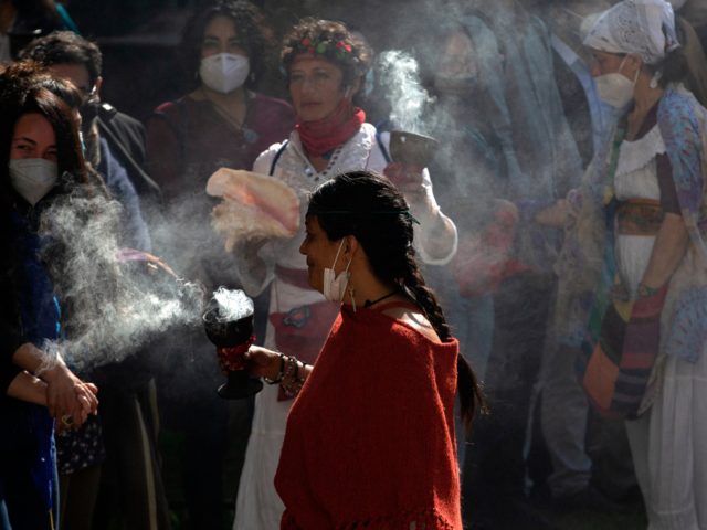 People participate in the ancestral Pawa indigenous ceremony, in gratitude to Mother Earth (Pachamama) outside the former congress in Santiago, on August 4, 2021. (Photo by CLAUDIO REYES / AFP) (Photo by CLAUDIO REYES/AFP via Getty Images)