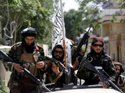 FILE - In this Aug. 19, 2021 file photo, Taliban fighters display their flag on patrol in