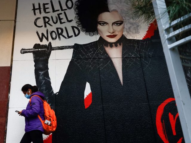 A masked pedestrian walks past a poster for the film Cruella in downtown Melbourne on Augu