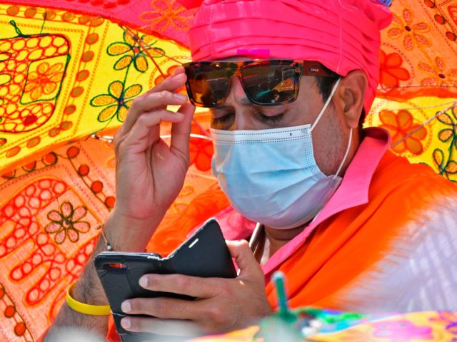 A traditionally dressed Indian fan looks at his mobile phone on the third day of the third cricket Test match between Australia and India at the Sydney Cricket Ground (SCG) in Sydney on January 9, 2021. (Photo by SAEED KHAN / AFP) / -- IMAGE RESTRICTED TO EDITORIAL USE - …