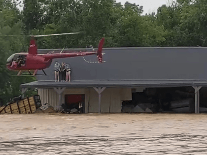 This image from video provided by Jeani Rice-Cranford shows Nashville-based helicopter pilot Joel Boyers rescuing people from a rooftop, Saturday, Aug. 21, 2021 in Waverly, Tenn. Boyers, who co-owns Helistar Aviation, said he ended up rescuing 17 people that day. He’s proud of that, but said he’s the one who …
