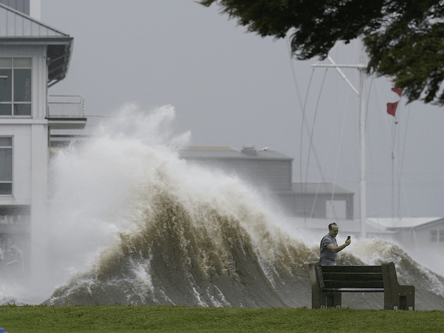 A man takes pictures of high waves along the shore of Lake Pontchartrain as Hurricane Ida