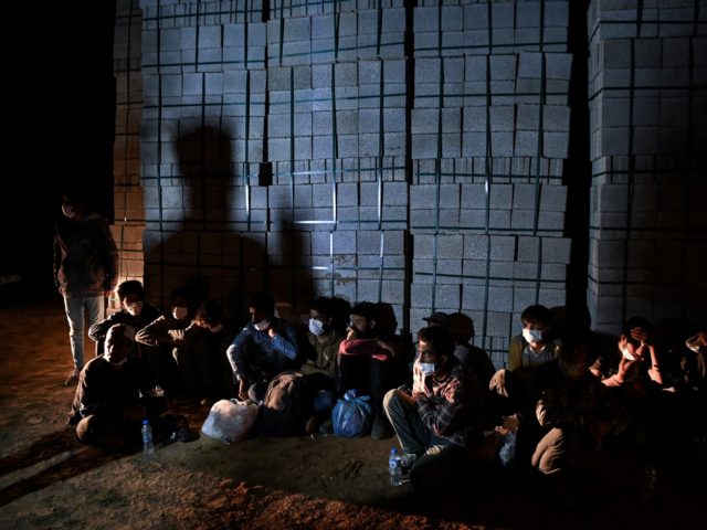 Afghan migrants rest while they wait for transport by smugglers after crossing the Iran-Tu