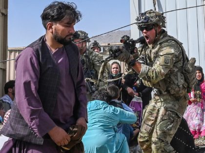 A US soldier (C) point his gun towards an Afghan passenger at the Kabul airport in Kabul on August 16, 2021, after a stunningly swift end to Afghanistan's 20-year war, as thousands of people mobbed the city's airport trying to flee the group's feared hardline brand of Islamist rule. (Photo …